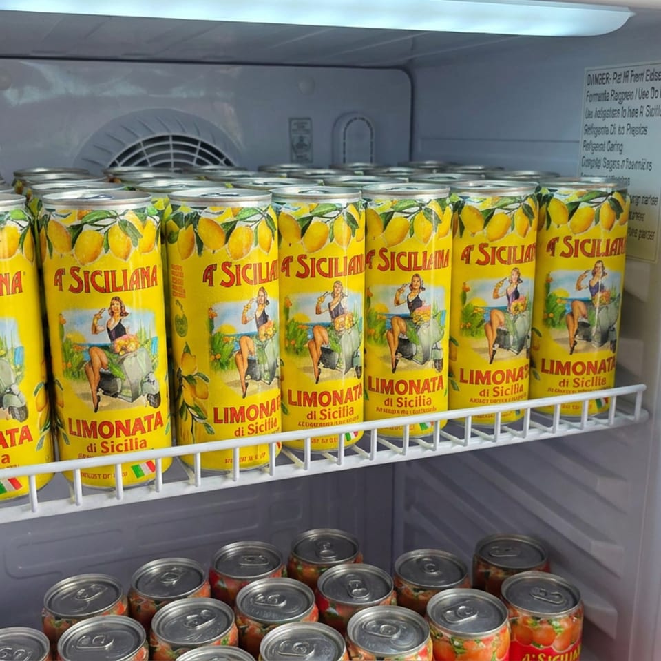 Refrigerator shelf stocked with bright yellow A Siciliana limonata cans featuring lemon illustrations.